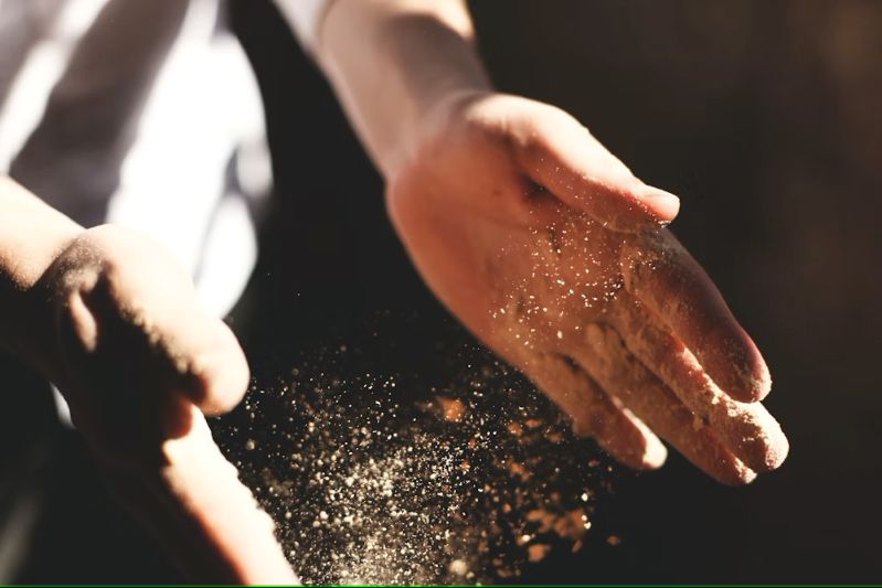 a pair of hands spaced apart with sand falling from them
